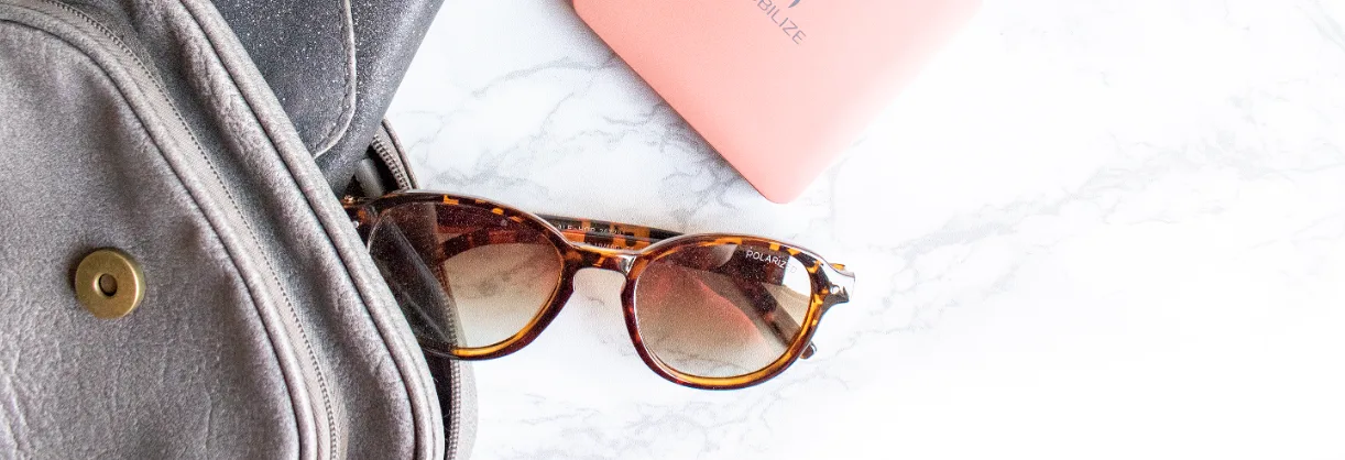 Flatlay of festival essentials like earplugs, wallet, power bank and small bag on a light surface