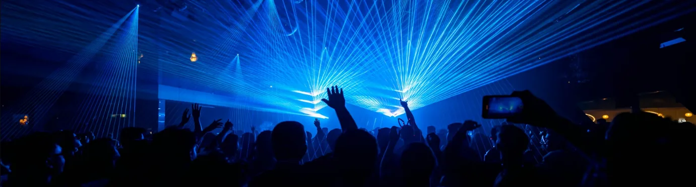 Hard techno crowd inside a dark venue with strobes and lasers above the dance floor